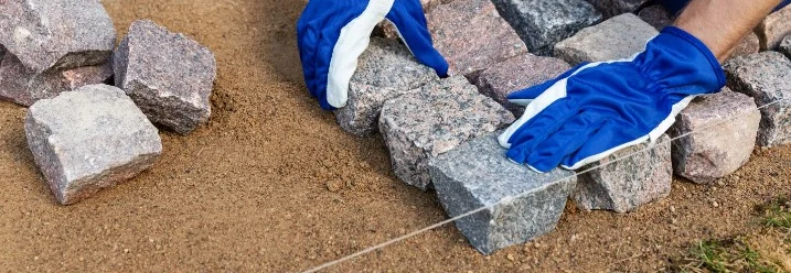 Person verlegt Pflastersteine